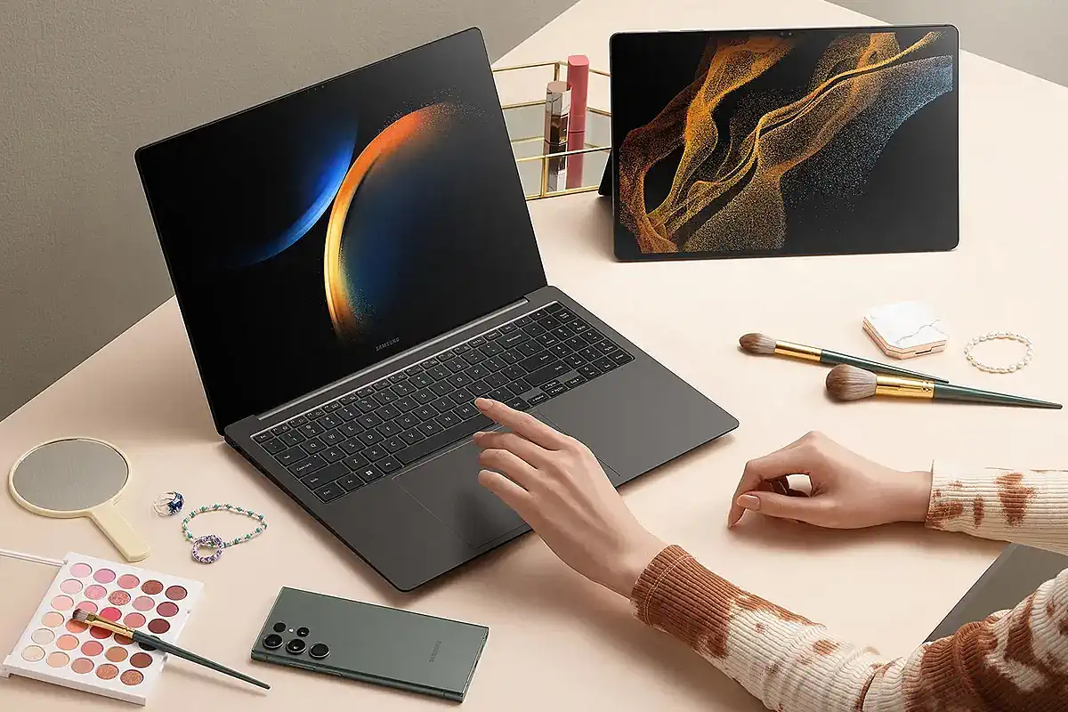 Mulher usando um notebook e um tablet Samsung lado a lado.